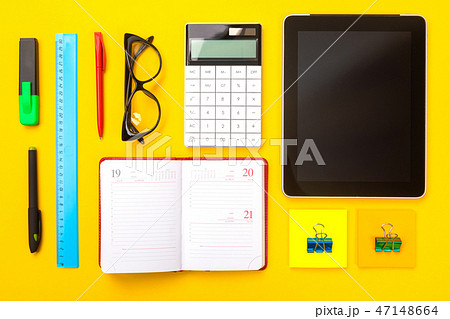 Top view of working space table with tablet, notebook and pen isolated on yellow background Top view of working space table with tablet, notebook and pen isolated on yellow background 47148664