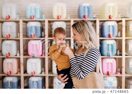 A young woman with a toddler boy buying liquids in zero waste shop. A young woman with a toddler boy buying liquids in zero waste shop. 47148665
