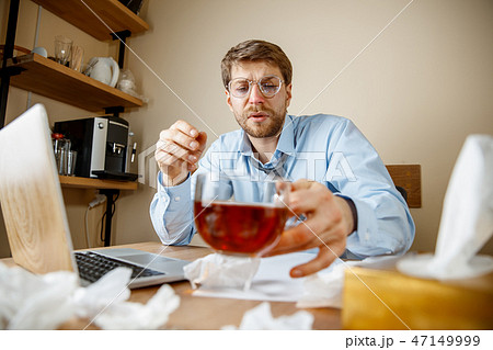 Sick man while working in office, businessman caught cold, seasonal flu. 47149999
