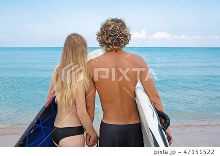 Surfers at the beach- Smiling couple of surfers walking on the beach and having fun in summer 47151522