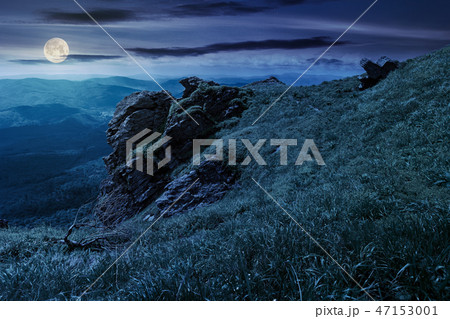 rocky formation on a grassy hillside at night rocky formation on a grassy hillside at night 47153001