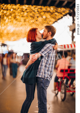 Happy couple embracing and kissing in the evening on a light garlands Happy couple embracing and kissing in the evening on a light garlands 47155683