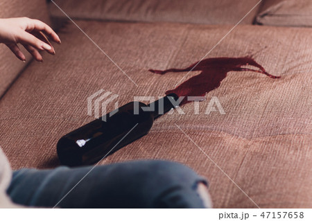 Red wine spilled on a brown couch sofa. dark bottle of red wine dropped 47157658