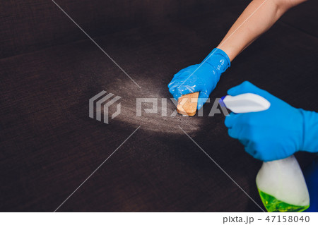 Cropped image. Cleaning concept. Male hand in protective gloves cleaning sofa couch in the room. Cropped image. Cleaning concept. Male hand in protective gloves cleaning sofa couch in the room. 47158040