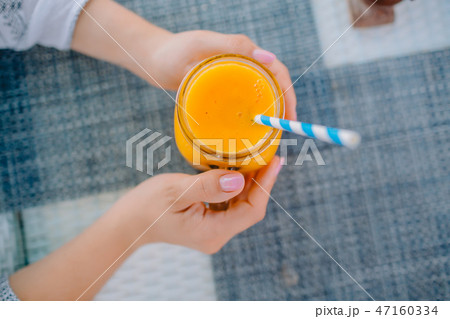 Woman hands and fresh orange juice with straw 47160334