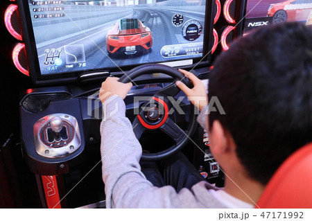 ゲームセンターでカーレースゲームを楽しむ少年 47171992