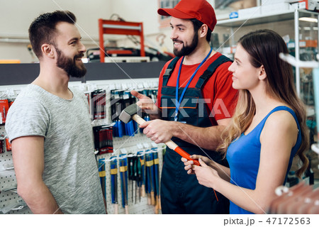 Salesman is showing couple of clients new hammer  47172563