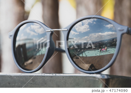 Swimming pool reflected in sunglasses in a tropical setting 47174090