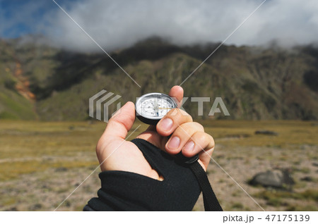 Viewpoint shot. A first-person view of a man's hand holds a compass against the background of an 47175139