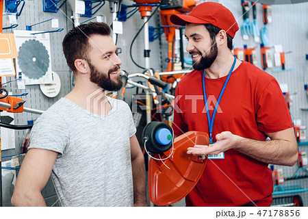Salesman is showing bearded client new lawn mower Salesman is showing bearded client new lawn mower 47178856