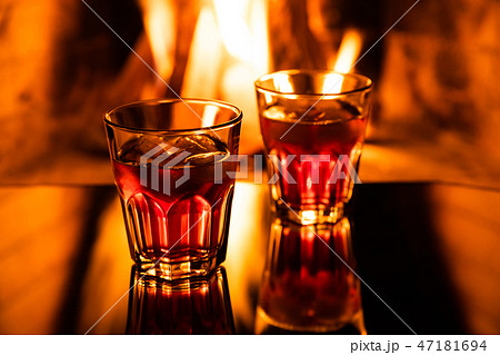 Glass of whiskey with ice near the fireplace 47181694