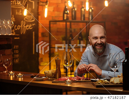 Middle-aged man sitting behind bar counter Middle-aged man sitting behind bar counter 47182187