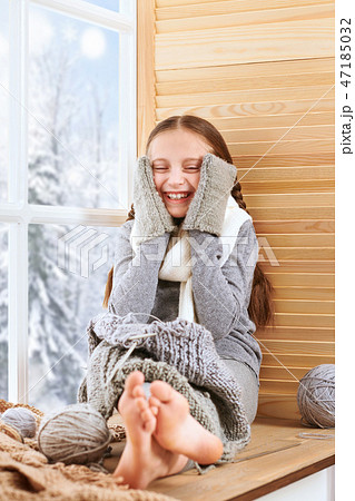 Child girl sitting on window sill with wool yarns Child girl sitting on window sill with wool yarns 47185032
