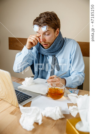 Feeling sick and tired. Frustrated young man massaging his head while sitting at his working place 47185250