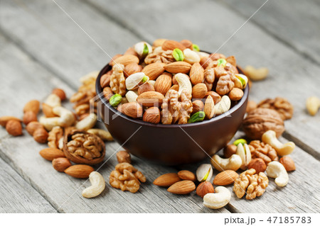 Wooden bowl with mixed nuts on a wooden gray background. Walnut, pistachios, almonds, hazelnuts and 47185783