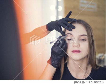 Artistic correction of eyebrows of a young girl. Tweezers, forceps. Beautiful Woman with long Artistic correction of eyebrows of a young girl. Tweezers, forceps. Beautiful Woman with long 47188445