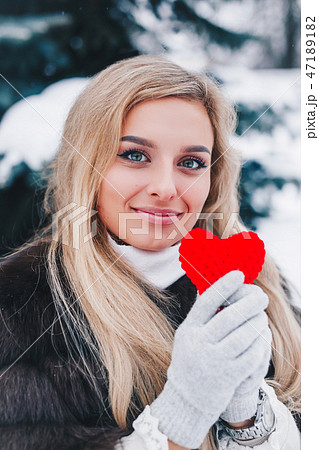 Portrait of a beautifull smiling woman in winter forest holding red Valentine's heart in the hands. Portrait of a beautifull smiling woman in winter forest holding red Valentine's heart in the hands. 47189182