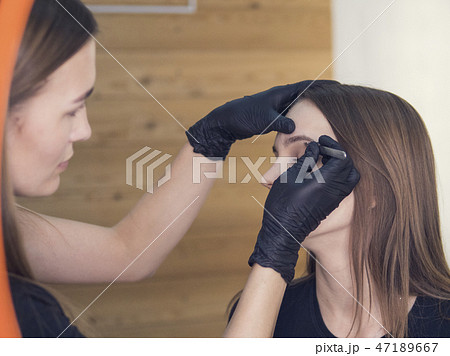 Artistic correction of eyebrows of a young girl. professional make-up in the beauty salon master Artistic correction of eyebrows of a young girl. professional make-up in the beauty salon master 47189667