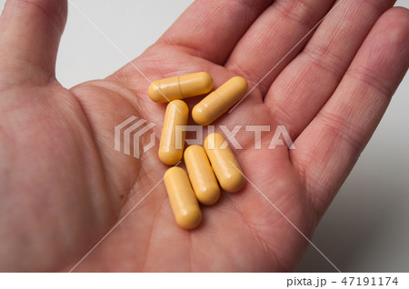 yellow drug capsules in hand of man  47191174