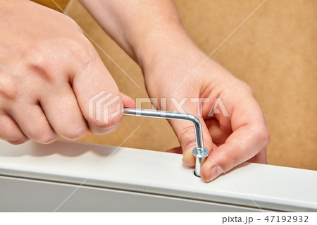 Repairman tightens confirmat screw into furniture Repairman tightens confirmat screw into furniture 47192932