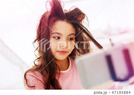 Cute funny girl feeling joyful while making hairstyle on her own at home Cute funny girl feeling joyful while making hairstyle on her own at home 47193884