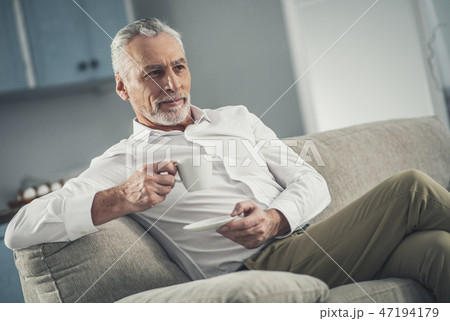 Man wearing white shirt drinking tea in the evening 47194179