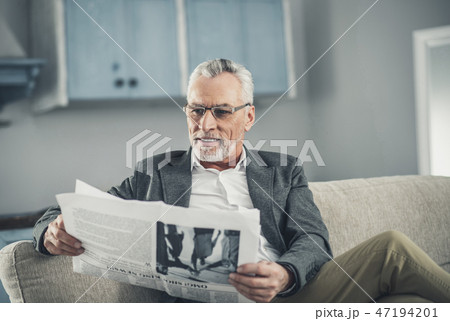 Grey-haired man wearing glasses reading positive news 47194201