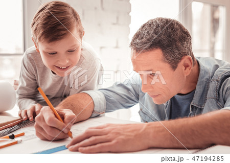 Blonde-haired son watching his father drawing figures for geometry class 47194285