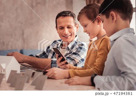 Blonde-haired son showing school photos to his father Blonde-haired son showing school photos to his father 47194361