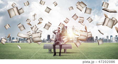 Many old books falling from above and student guy sitting on ben Many old books falling from above and student guy sitting on ben 47202086