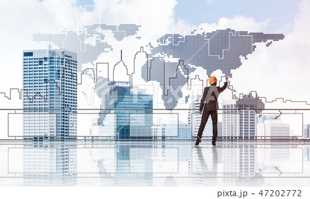 Sunrise above skyscrapers and engineer in helmet drawing globali Sunrise above skyscrapers and engineer in helmet drawing globali 47202772
