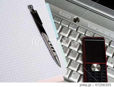 Business. Phone and notepad on laptop. 47206305
