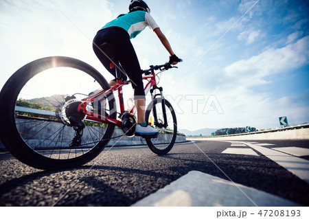Woman cyclist legs riding Mountain Bike on highway Woman cyclist legs riding Mountain Bike on highway 47208193