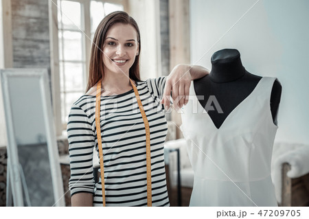 Beaming fashion designer smiling while standing near dress form 47209705