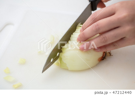 白い背景にまな板で玉ねぎを女性の手でみじん切り 47212440