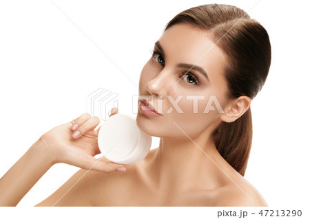 Cute girl preparing to start her day. She is applying moisturizer cream on face. Cute girl preparing to start her day. She is applying moisturizer cream on face. 47213290