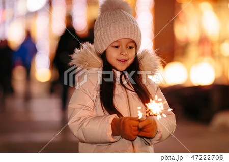 Cute smiling little girl with bengal lights on the street in the evening 47222706