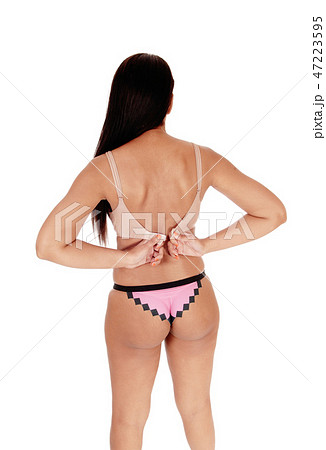 Woman standing in panties, closing her bra Woman standing in panties, closing her bra 47223595