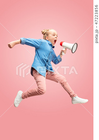 Beautiful young child teen girl jumping with megaphone isolated over pink background 47223856
