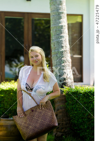 Young blonde beautiful woman in see-through beach dress and bikini near luxury tropical villa with Young blonde beautiful woman in see-through beach dress and bikini near luxury tropical villa with 47225479