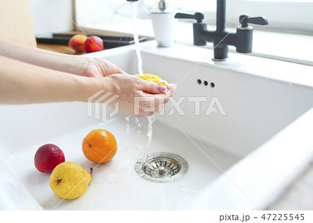 Woman washing fruits in the sink home kitchen Woman washing fruits in the sink home kitchen 47225545