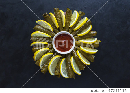 Stuffed Grape Leaves served with lemon. Top view. Stuffed Grape Leaves served with lemon. Top view. 47231112
