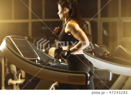 Young attractive woman running on treadmill 47243283