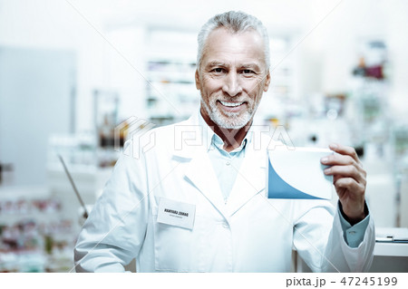 Pleased mature pharmacist demonstrating box with tablets Pleased mature pharmacist demonstrating box with tablets 47245199
