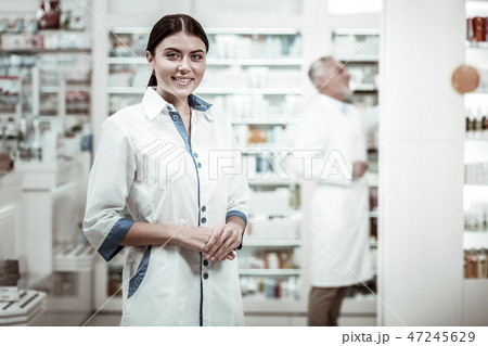 Green-eyed pharmacist. Appealing green-eyed pharmacist smiling broadly while meeting clients in 47245629