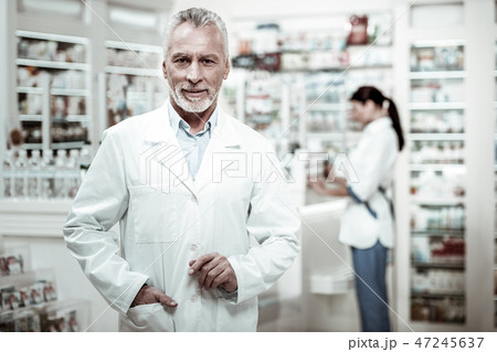 Senior pharmacist coming to the drugstore checking the work of his employees 47245637