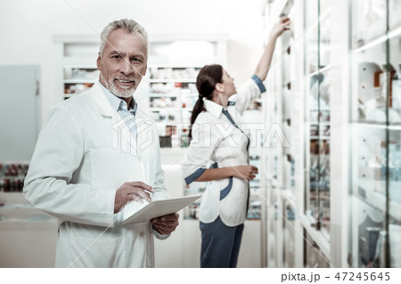 Mature prosperous director of drugstore holding tablet while making order Mature prosperous director of drugstore holding tablet while making order 47245645