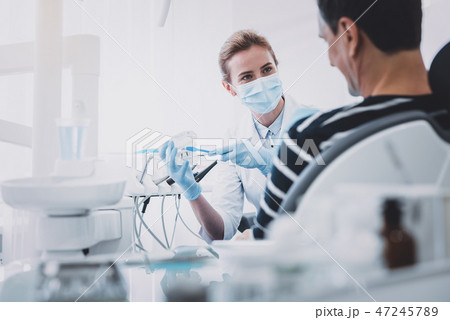 Positive delighted blonde woman cleaning artificial teeth 47245789