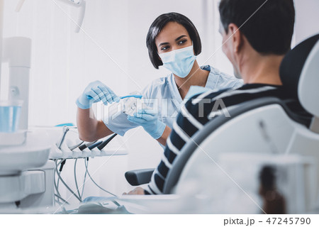 Pleased brunette stomatologist showing the way of teeth care 47245790