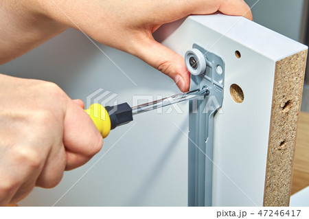 Furniture assembler tightens screw in drawer slide 47246417